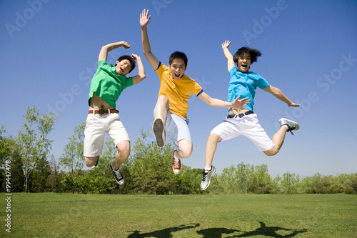 Three young men jumping in the air at the park