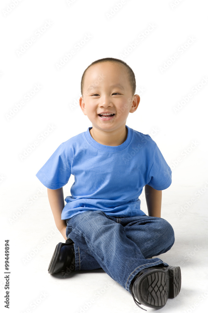 Young boy sits on the ground and smiles Young boy sits on the ground and smiles