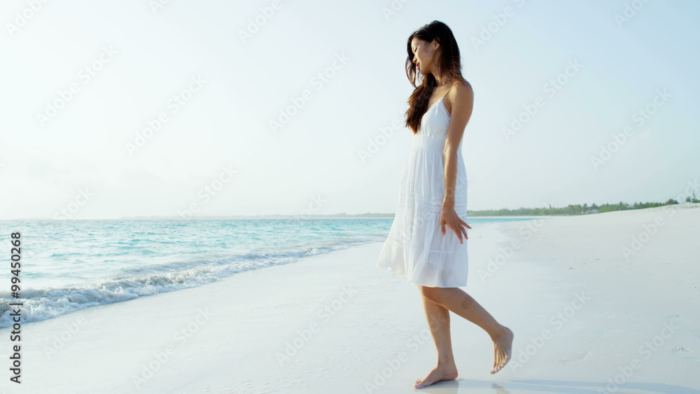 Asian American girl walking barefoot by tropical ocean Asian American girl walking barefoot by tropical ocean
