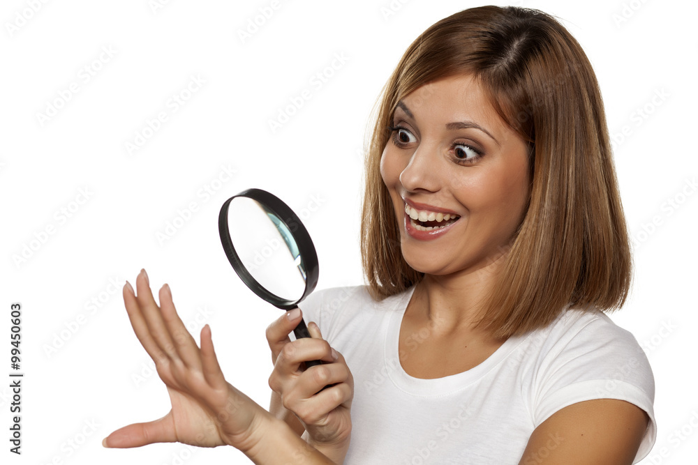 beautiful happy woman looking her nails with a magnifying glass beautiful happy woman looking her nails with a magnifying glass