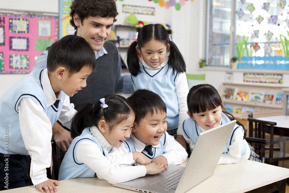Students and teacher gathered around a computer in the classroom Students and teacher gathered around a computer in the classroom