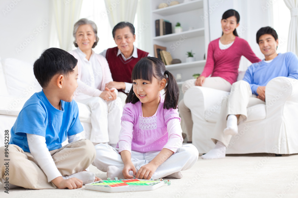Chinese children playing with toys on the floor with grandparents and parents behind them Chinese children playing with toys on the floor with grandparents and parents behind them