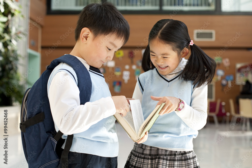 Young students huddle together reading a book Young students huddle together reading a book