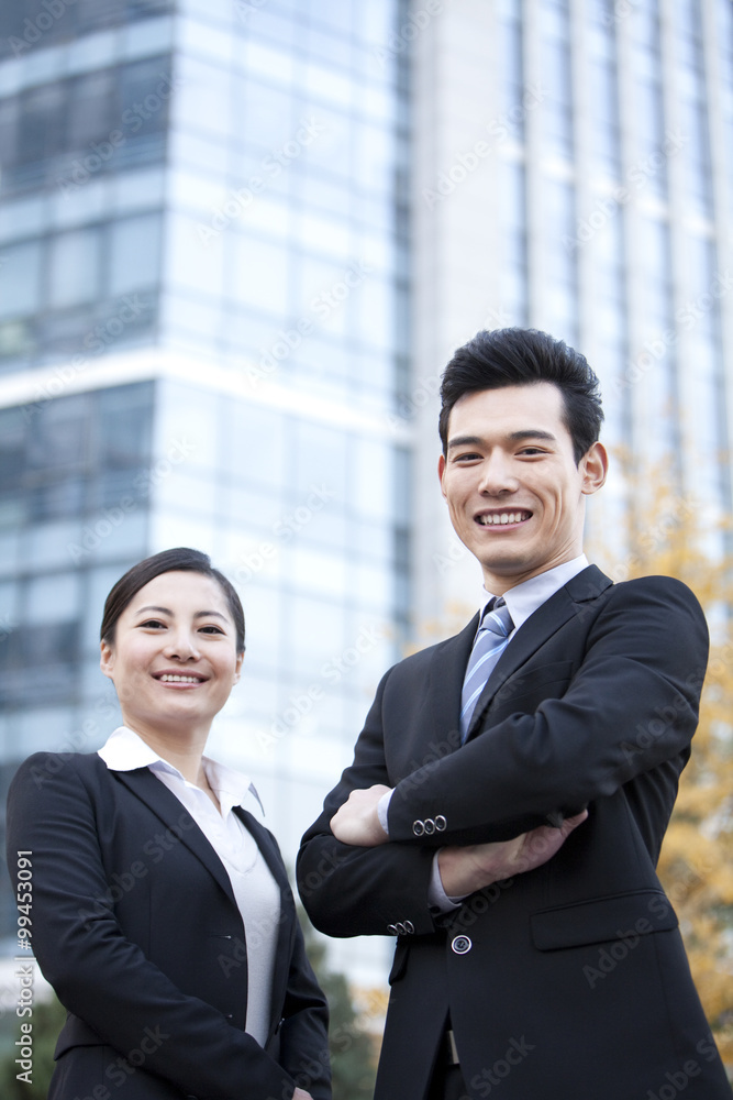 A businessman and businesswoman outside office buildings A businessman and businesswoman outside office buildings