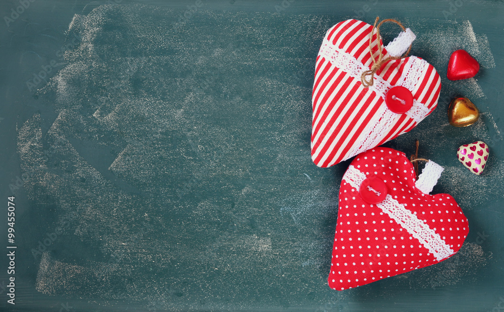 Obraz premium top view image of colorful heart shape chocolates, fabric hearts on blackboard background. valentine's day celebration concept 