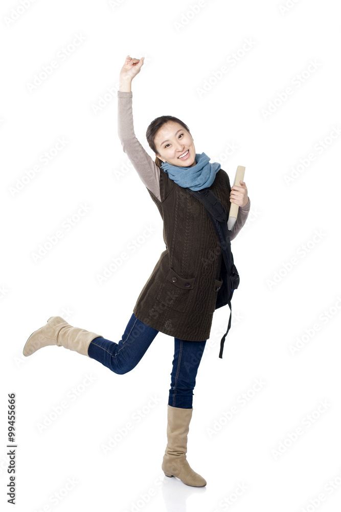 Playful young female student standing on one leg and holding arm up in the air, white background Playful young female student standing on one leg and holding arm up in the air, white background
