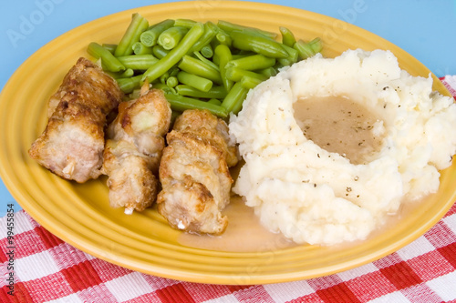 City Chicken with Mashed Potatoes – City chicken (cubes of pork on a skewer, a midwest favorite) with mashed potatoes, gravy, and green beans on a plate.