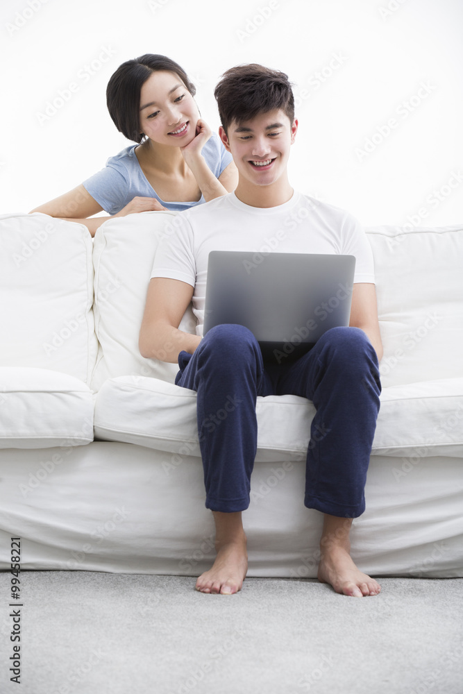 Young couple using laptop on couch Young couple using laptop on couch