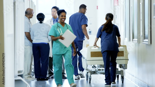 Positive multi ethnic team of hospital staff work and consult with senior couple