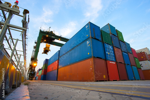 Cranes and multi-colored stack of cargo containers at dusk