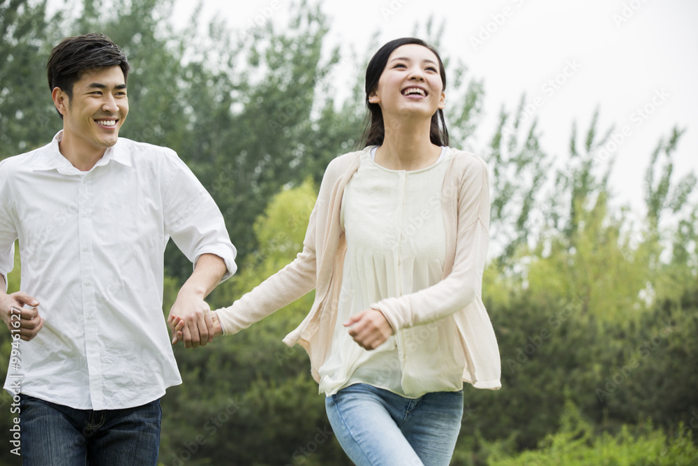 Happy young couple holding hands running Happy young couple holding hands running