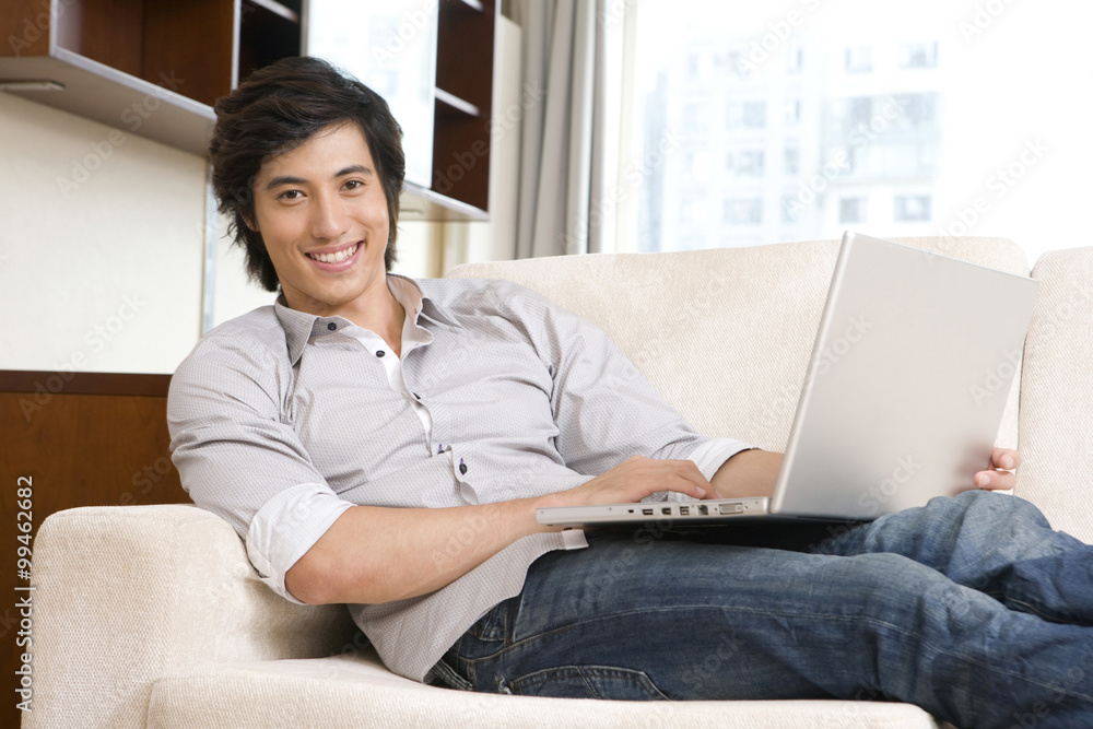 Asian man on sofa with laptop