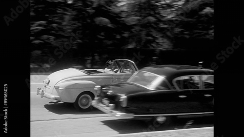Car stopping by broken down police car on road, 1950s