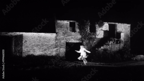 Woman running past an abandoned building at night  photo