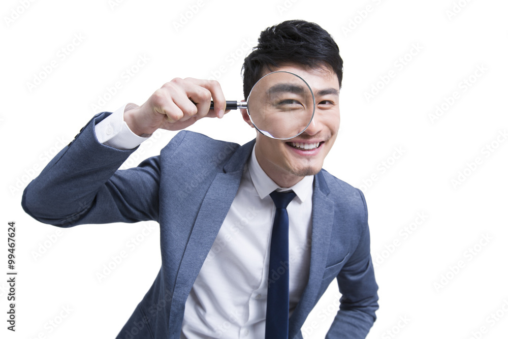 Young businessman looking through magnifying glass Young businessman looking through magnifying glass