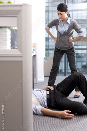 Businesswoman angry at her colleague lying on the floor