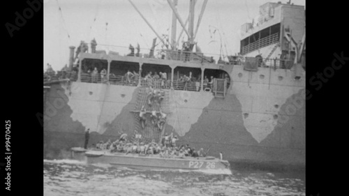 Soldiers climbing down rope ladder to landing crafts