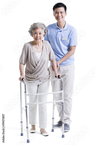 Male nursing assistant helping senior woman with walking frame © Blue Jean Images