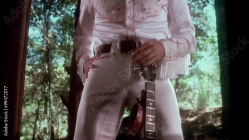 Tilt up shot of  Elvis impersonator with guitar photo