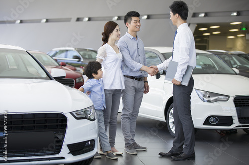 Young family choosing car in showroom