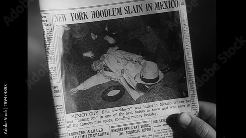 Close-up of person looking at newspaper photo of slain gangster, 1940s