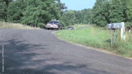 Police car chasing man in station wagon on country road