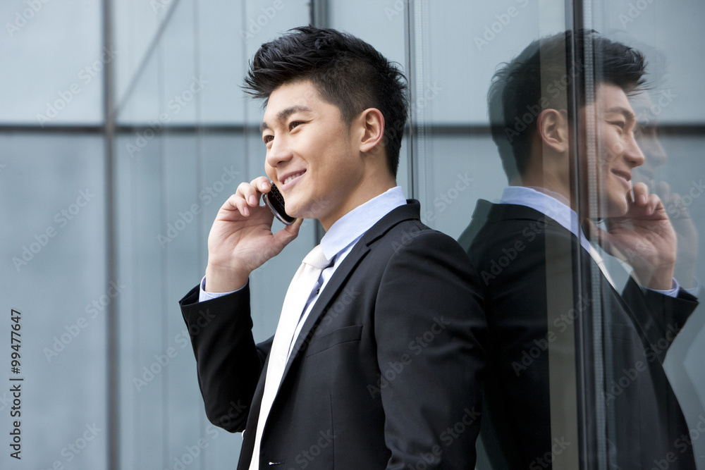 Businessman on the phone leaning against the wall