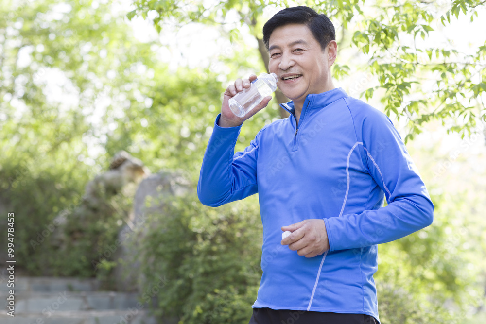 Happy mature man drinking water after exercising Happy mature man drinking water after exercising