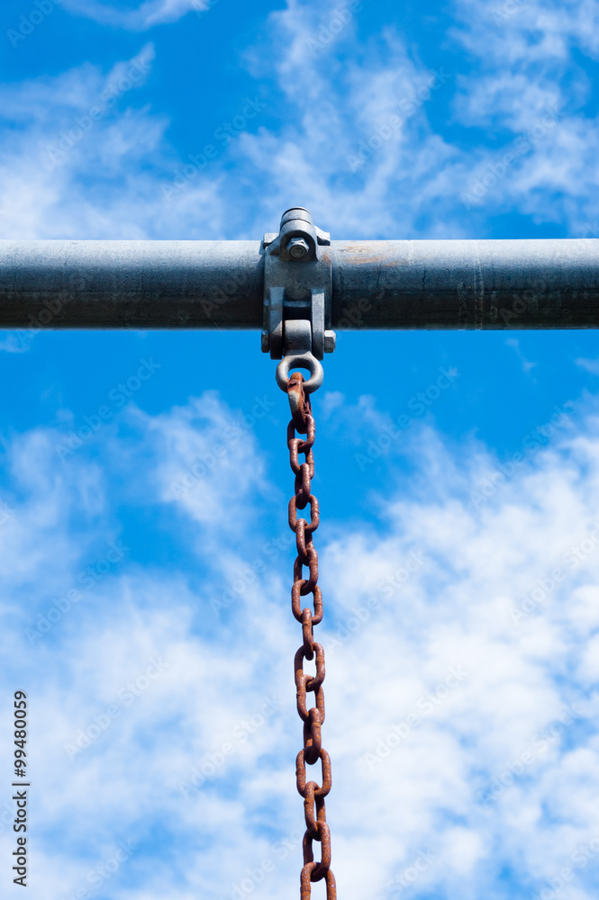 Metal bar with rusted chain hanging against sky Metal bar with rusted chain hanging against sky