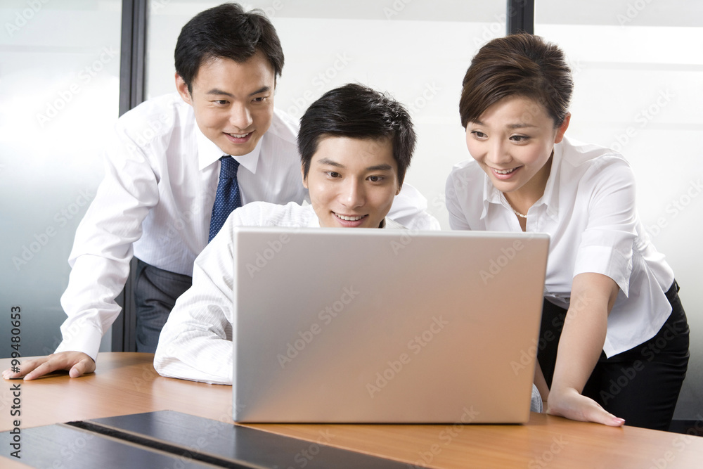Young businessmen and businesswoman using laptop in office Young businessmen and businesswoman using laptop in office