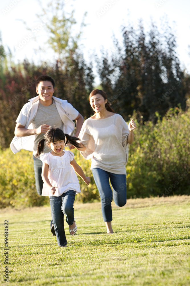 Young Chinese family running in a field Young Chinese family running in a field