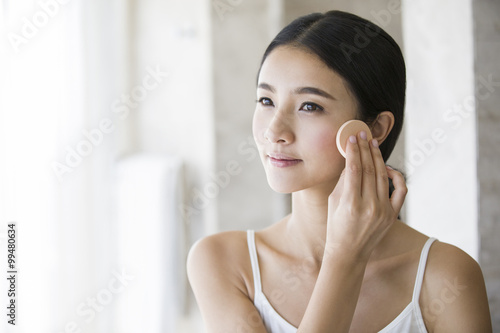 Young woman applying facial powder