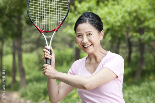 Senior woman playing tennis in park © Blue Jean Images