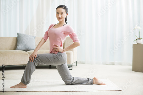 Young woman practicing yoga in living room