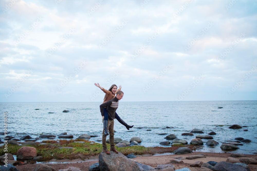 a man wearing a girl on his back on the rocky beach