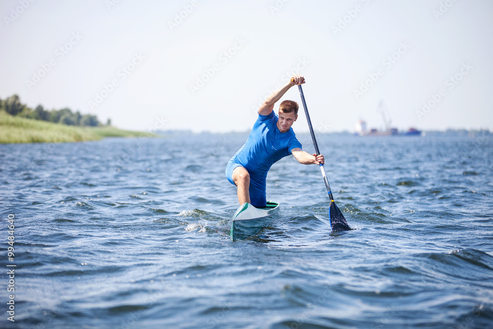 Young man rowing in canoe along a river Young man rowing in canoe along a river
