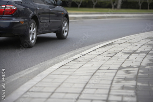 Low Angle View Of A Concrete Block Pavement With A Car Driving Past