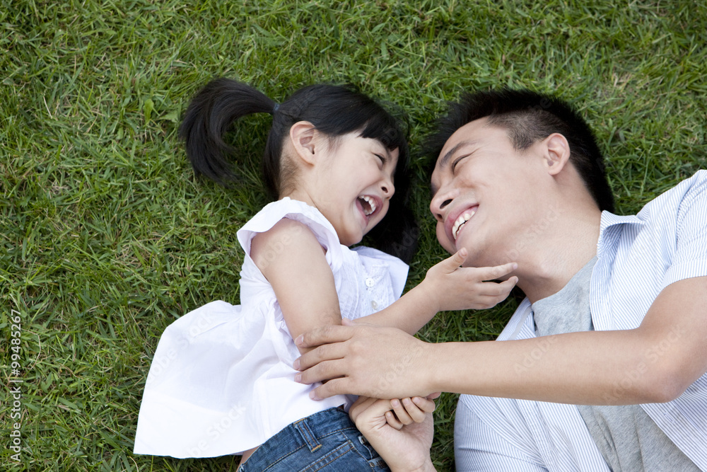 Happy father and daughter lying down on the grass Happy father and daughter lying down on the grass