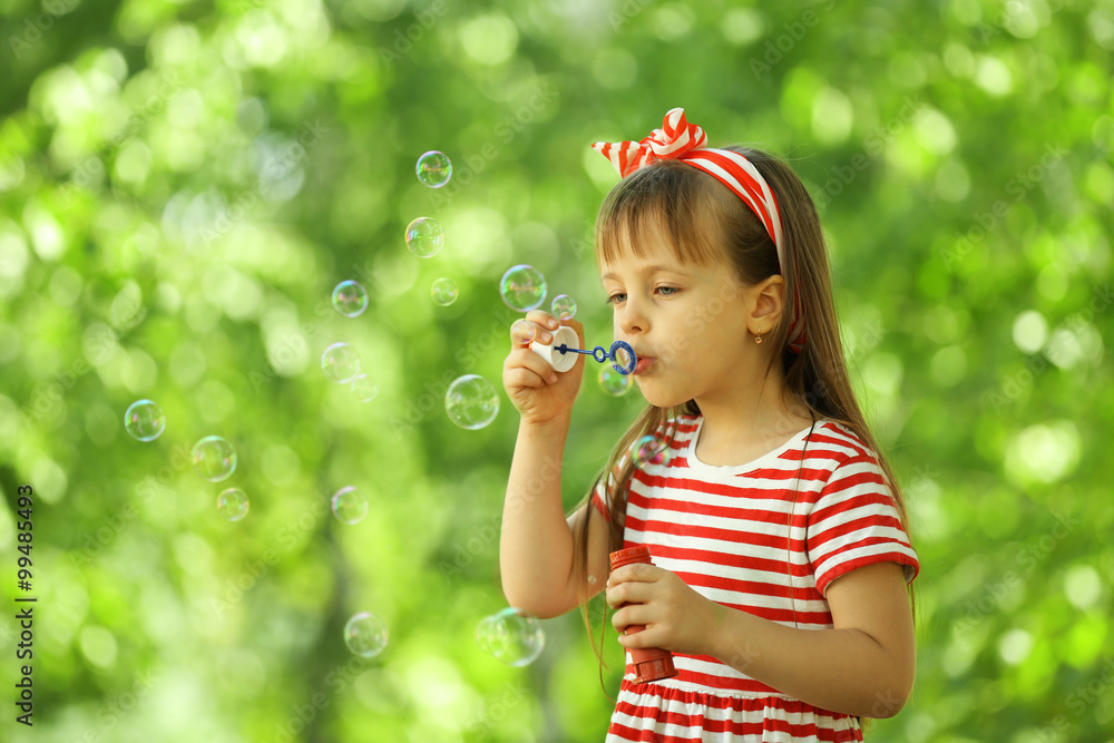 Little girl playing with bubbles in the park