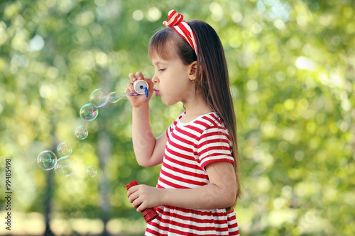 Little girl playing with bubbles in the park