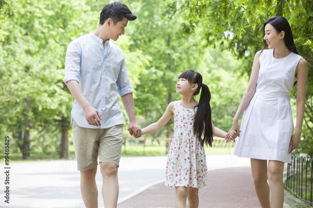 Happy young family walking together in park Happy young family walking together in park