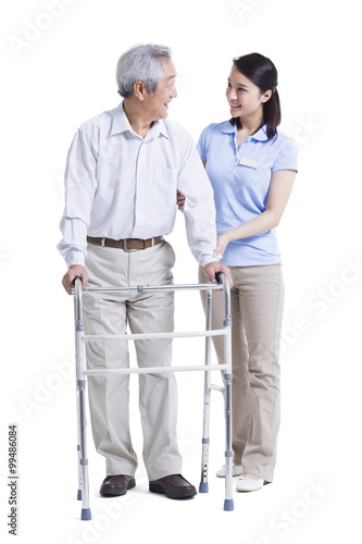 Female nursing assistant helping senior man with walking frame © Blue Jean Images