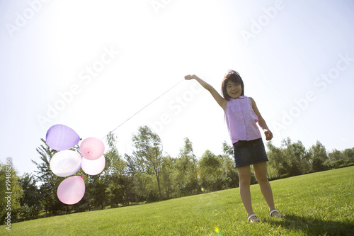 Young girl running with balloon outdoors © Blue Jean Images