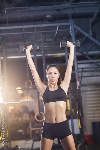 Young woman lifting weights at gym
