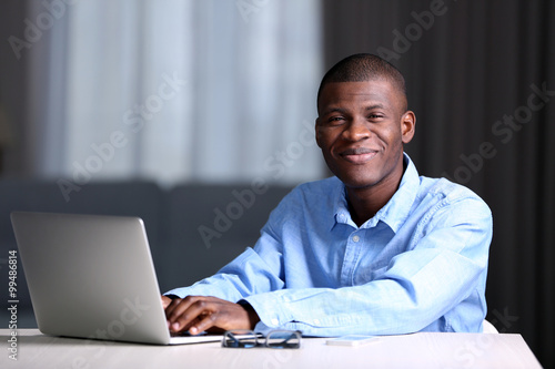 Canvas Print African American businessman in blue shirt with laptop, close up