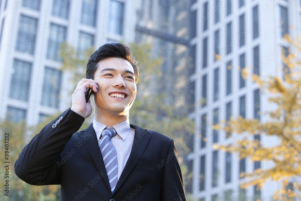 Businessman outside buildings on his mobile phone Businessman outside buildings on his mobile phone
