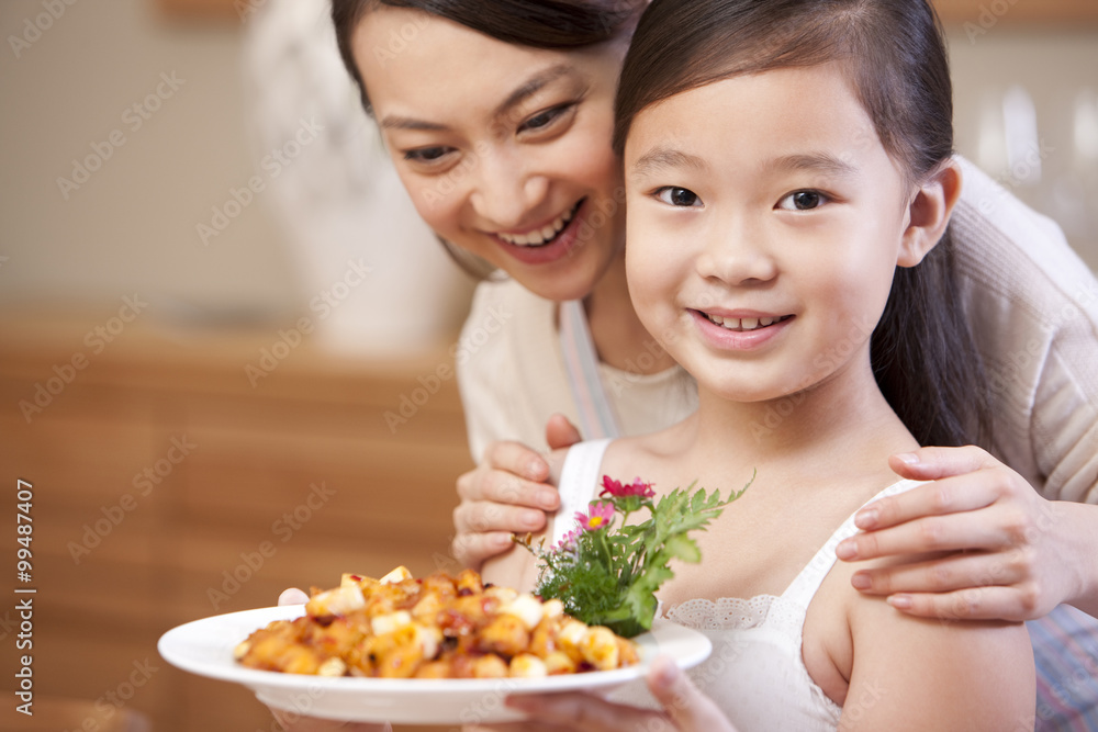 Mother and daughter with a plate of Kung Pao Chicken, Chinese dish Mother and daughter with a plate of Kung Pao Chicken, Chinese dish