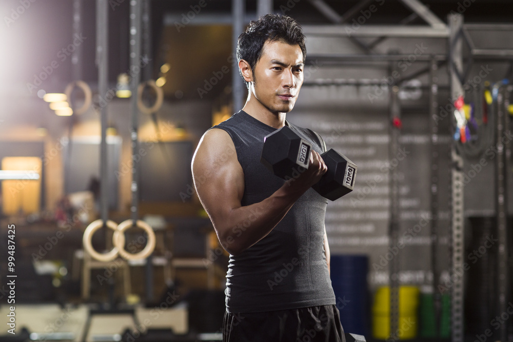 Young man lifting weights at gym Young man lifting weights at gym