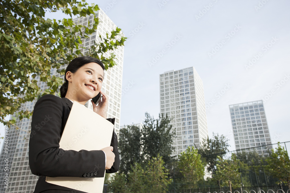 Young businesswoman with a folder talking on the phone in downtown district