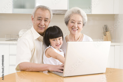 Little girl using a laptop with her grandparents